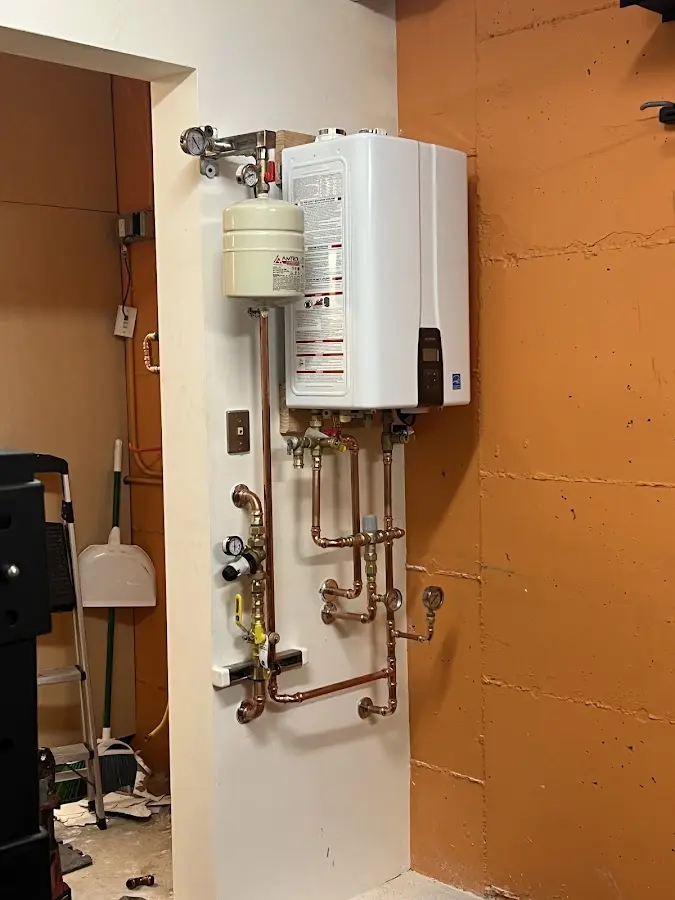 Plumbing technician inspecting water heater connections in Stanley